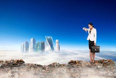 La mujer de negocios se coloca al borde de la montaña y de la mirada en ciudad imagen de archivo La mujer de negocios se coloca al borde de la montaña y de la mirada en ciudad imagen de archivo