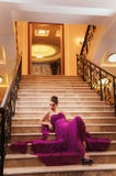 La mujer en un vestido largo se está sentando en las escaleras Imagen de archivo libre de regalías La mujer en un vestido largo se está sentando en las escaleras Imagen de archivo libre de regalías