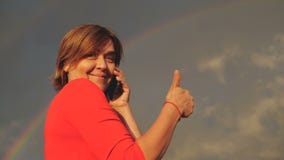 La mujer envejecida centro feliz muestra el pulgar y habla con el teléfono en la cámara lenta metrajes La mujer envejecida centro feliz muestra el pulgar y habla con el teléfono en la cámara lenta metrajes