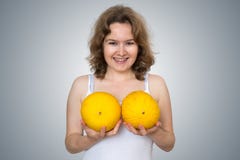 La mujer hermosa joven sostiene los melones en manos sobre su cirugía plástica del pecho y el silicón implanta concepto fotografía de archivo La mujer hermosa joven sostiene los melones en manos sobre su cirugía plástica del pecho y el silicón implanta concepto fotografía de archivo