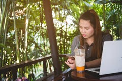 La mujer hermosa utilizó el smartphone, ordenador portátil y heló té en la tabla de fotos de archivo libres de regalías La mujer hermosa utilizó el smartphone, ordenador portátil y heló té en la tabla de fotos de archivo libres de regalías