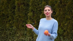 La mujer joven del retrato se considera anaranjado y juega con él y sonrisas lindas La mujer joven del retrato se considera anaranjado y juega con él y sonrisas lindas