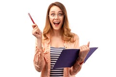 La mujer joven hermosa con la expresión alegre lleva el lápiz y la libreta, abre la boca extensamente, hace notas en cuaderno imagen de archivo libre de regalías La mujer joven hermosa con la expresión alegre lleva el lápiz y la libreta, abre la boca extensamente, hace notas en cuaderno imagen de archivo libre de regalías