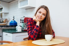 La mujer joven sonriente hermosa que se sienta encendido kithen y café de consumición fotos de archivo libres de regalías La mujer joven sonriente hermosa que se sienta encendido kithen y café de consumición fotos de archivo libres de regalías