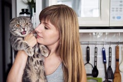 La mujer rubia joven feliz en la camiseta casual que detiene a escocés magnífico dobla el gato en la cocina nacional Retrato natu fotos de archivo libres de regalías La mujer rubia joven feliz en la camiseta casual que detiene a escocés magnífico dobla el gato en la cocina nacional Retrato natu fotos de archivo libres de regalías