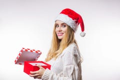 La mujer rubia sonriente alegre alegre en un sombrero y un suéter rojos de Papá Noel abrió su regalo del Año Nuevo, una caja y mi foto de archivo La mujer rubia sonriente alegre alegre en un sombrero y un suéter rojos de Papá Noel abrió su regalo del Año Nuevo, una caja y mi foto de archivo