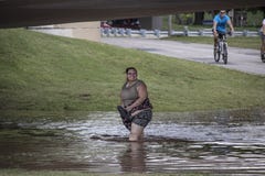 La mujer sonríe mientras que ella vadea a través del agua de inundación asquerosa debajo del paso inferior por el río Arkansas du foto de archivo La mujer sonríe mientras que ella vadea a través del agua de inundación asquerosa debajo del paso inferior por el río Arkansas du foto de archivo