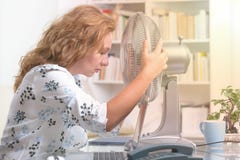 La mujer sufre de calor en la oficina o en casa imagen de archivo La mujer sufre de calor en la oficina o en casa imagen de archivo