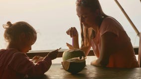 La mère et la fille s'assied au café de seaview avec des noix de coco image stock La mère et la fille s'assied au café de seaview avec des noix de coco image stock