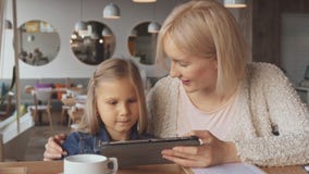 La mère et la fille utilisent le comprimé au café image stock La mère et la fille utilisent le comprimé au café image stock