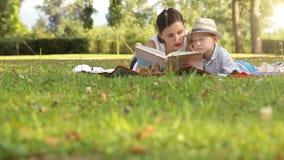 La mère et le fils passent le temps en parc en été lisant un livre clips vidéos La mère et le fils passent le temps en parc en été lisant un livre clips vidéos