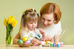 La mère heureuse enseigne la fille d'enfant à décorer des oeufs de pâques Image libre de droits La mère heureuse enseigne la fille d'enfant à décorer des oeufs de pâques Image libre de droits
