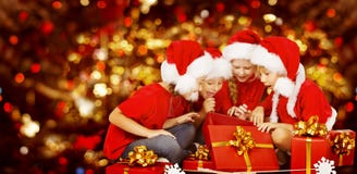 La Navidad embroma la actual caja de regalo de apertura, niños en Santa Hat Foto de archivo libre de regalías La Navidad embroma la actual caja de regalo de apertura, niños en Santa Hat Foto de archivo libre de regalías