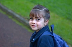 La niña feliz camina a la escuela que mira detrás sobre su shoulde fotos de archivo libres de regalías La niña feliz camina a la escuela que mira detrás sobre su shoulde fotos de archivo libres de regalías