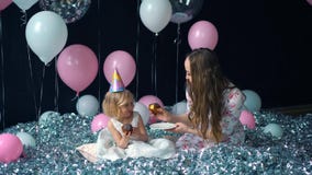 La niña linda y su mamá joven hermosa comen las magdalenas, fiesta de cumpleaños, celebración de días festivos En el fondo de glo almacen de metraje de vídeo La niña linda y su mamá joven hermosa comen las magdalenas, fiesta de cumpleaños, celebración de días festivos En el fondo de glo almacen de metraje de vídeo