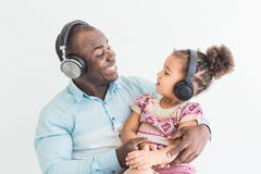 La niña linda y su papá están escuchando la música con los auriculares en un fondo blanco imágenes de archivo libres de regalías La niña linda y su papá están escuchando la música con los auriculares en un fondo blanco imágenes de archivo libres de regalías