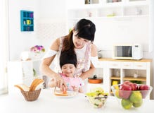La niña que ayuda a su madre prepara la comida en la cocina foto de archivo libre de regalías La niña que ayuda a su madre prepara la comida en la cocina foto de archivo libre de regalías