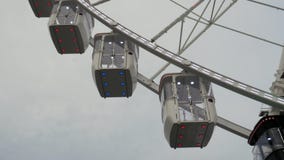La noria hace girar contra el cielo gris nublado, tempestuoso Ciérrese para arriba de las cabinas de la noria con la iluminación almacen de metraje de vídeo La noria hace girar contra el cielo gris nublado, tempestuoso Ciérrese para arriba de las cabinas de la noria con la iluminación almacen de metraje de vídeo