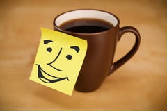 La note de post-it avec le visage souriant sticked sur une tasse Photos libres de droits La note de post-it avec le visage souriant sticked sur une tasse Photos libres de droits