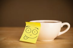 La note de post-it avec le visage souriant sticked sur une tasse Image libre de droits La note de post-it avec le visage souriant sticked sur une tasse Image libre de droits