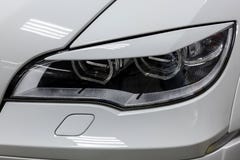 La opini?n delantera del faro del coche usado blanco se coloca en la venta auto de la sala de exposici?n despu?s del lavado y el foto de archivo libre de regalías La opini?n delantera del faro del coche usado blanco se coloca en la venta auto de la sala de exposici?n despu?s del lavado y el foto de archivo libre de regalías