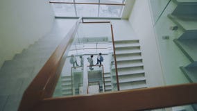 La opinión superior dos hombres de negocios se encuentra en las escaleras en centro moderno y hablar de la oficina mientras que t La opinión superior dos hombres de negocios se encuentra en las escaleras en centro moderno y hablar de la oficina mientras que t