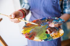 La paleta con las pinturas mezcladas holded por las manos del artista de la mujer foto de archivo La paleta con las pinturas mezcladas holded por las manos del artista de la mujer foto de archivo