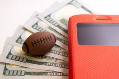 La palla per rugby o football americano si trova accanto al telefono in una cassa rossa contro lo sfondo di cinquecento dollari a fotografia stock libera da diritti La palla per rugby o football americano si trova accanto al telefono in una cassa rossa contro lo sfondo di cinquecento dollari a fotografia stock libera da diritti