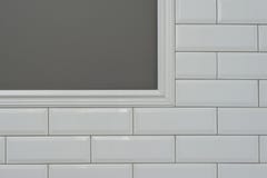 La pared pintada gris, pieza de la pared es pequeño ladrillo brillante blanco cubierto de las tejas, tejas decorativas de cerámic imagenes de archivo La pared pintada gris, pieza de la pared es pequeño ladrillo brillante blanco cubierto de las tejas, tejas decorativas de cerámic imagenes de archivo