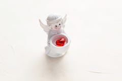 La pequeña figurilla de un ángel con un corazón rojo está en blanco imagen de archivo La pequeña figurilla de un ángel con un corazón rojo está en blanco imagen de archivo