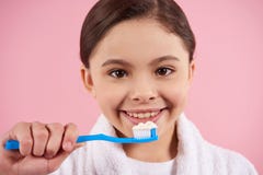 La petite fille dans le peignoir brosse des dents images stock La petite fille dans le peignoir brosse des dents images stock