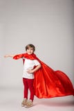 La petite fille feignent la superwoman dans le cap rouge images libres de droits La petite fille feignent la superwoman dans le cap rouge images libres de droits