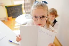 La petite écolière mignonne en verres montre son cahier photo stock La petite écolière mignonne en verres montre son cahier photo stock