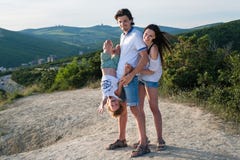 La photo de famille dans les montagnes avec l'enfant portant le fils léger d'habillement accrochant dans le ` s de papa remet à l photo stock La photo de famille dans les montagnes avec l'enfant portant le fils léger d'habillement accrochant dans le ` s de papa remet à l photo stock