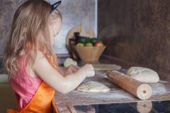 La piccola bella ragazza sveglia in grembiule arancio che sorride e che produce la pizza casalinga, rotola la cucina della pasta immagine stock La piccola bella ragazza sveglia in grembiule arancio che sorride e che produce la pizza casalinga, rotola la cucina della pasta immagine stock
