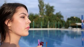 La ragazza attraente beve il cocktail vicino al Poolside sulle vacanze estive stock footage La ragazza attraente beve il cocktail vicino al Poolside sulle vacanze estive stock footage