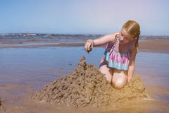 La ragazza bulding i castelli di sabbia sulla spiaggia immagini stock libere da diritti La ragazza bulding i castelli di sabbia sulla spiaggia immagini stock libere da diritti