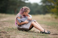 La ragazza del bambino si siede su erba con suo fratello neonato sulla passeggiata nella parità fotografie stock libere da diritti La ragazza del bambino si siede su erba con suo fratello neonato sulla passeggiata nella parità fotografie stock libere da diritti