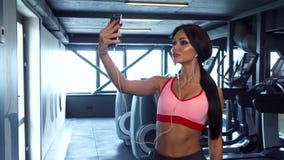 La ragazza dolce sta facendo il selfie sui precedenti della palestra stock footage La ragazza dolce sta facendo il selfie sui precedenti della palestra stock footage
