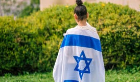 La ragazza ebrea di vista posteriore con la bandiera israeliana la ha avvolta fotografia stock libera da diritti La ragazza ebrea di vista posteriore con la bandiera israeliana la ha avvolta fotografia stock libera da diritti