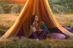 La ragazza indiana lussuosa sta sedendosi in una tenda all'aperto, al tramonto royalty illustrazione gratis La ragazza indiana lussuosa sta sedendosi in una tenda all'aperto, al tramonto royalty illustrazione gratis