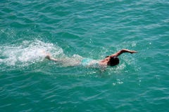 La ragazza nuota lo stile libero nel mare fotografia stock La ragazza nuota lo stile libero nel mare fotografia stock