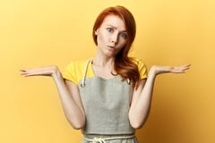La ragazza pensierosa in grembiule grigio non conosce la risposta della domanda immagini stock libere da diritti La ragazza pensierosa in grembiule grigio non conosce la risposta della domanda immagini stock libere da diritti