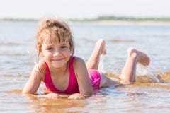 La ragazza quinquennale si trova in acqua in secca del fiume e di esame della struttura fotografia stock La ragazza quinquennale si trova in acqua in secca del fiume e di esame della struttura fotografia stock