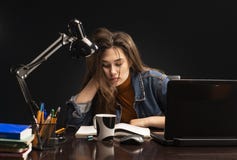 La ragazza sta sedendosi alla tavola ed allo studio fotografia stock libera da diritti La ragazza sta sedendosi alla tavola ed allo studio fotografia stock libera da diritti