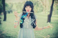 La ragazza tailandese asiatica sveglia sta soffiando le bolle di sapone nel parco nel Dott. fotografia stock La ragazza tailandese asiatica sveglia sta soffiando le bolle di sapone nel parco nel Dott. fotografia stock