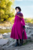 La ragazza in un cappotto cremisi luminoso esamina la distanza Fotografie Stock Libere da Diritti La ragazza in un cappotto cremisi luminoso esamina la distanza Fotografie Stock Libere da Diritti