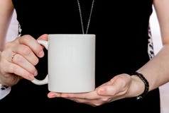 La ragazza in vestito nero sta tenendo la tazza bianca in mani immagini stock libere da diritti La ragazza in vestito nero sta tenendo la tazza bianca in mani immagini stock libere da diritti