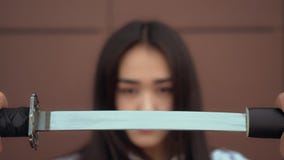 La scolara giapponese tira il katana dalla guaina con il fronte serio Signora di Confidend video d archivio La scolara giapponese tira il katana dalla guaina con il fronte serio Signora di Confidend video d archivio