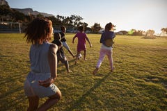 La scuola elementare scherza giocar a calcioe in un campo, vista posteriore fotografia stock La scuola elementare scherza giocar a calcioe in un campo, vista posteriore fotografia stock